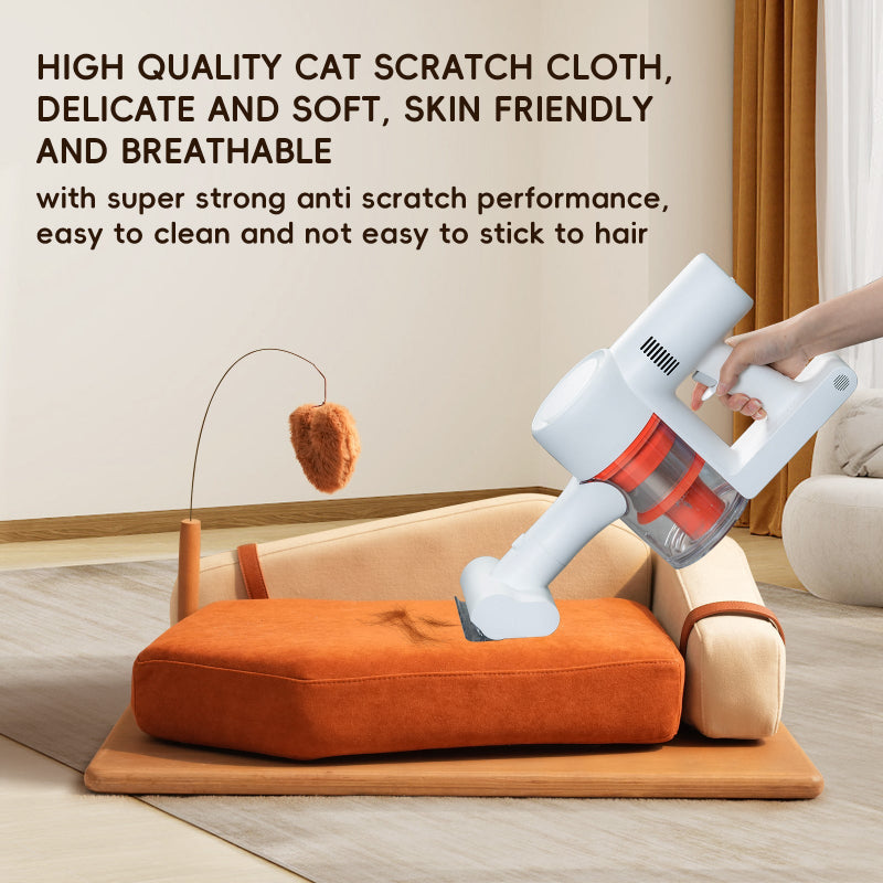 A hand using a handheld vacuum cleaner to remove pet hair from an orange scratch-resistant fabric cat sofa bed.