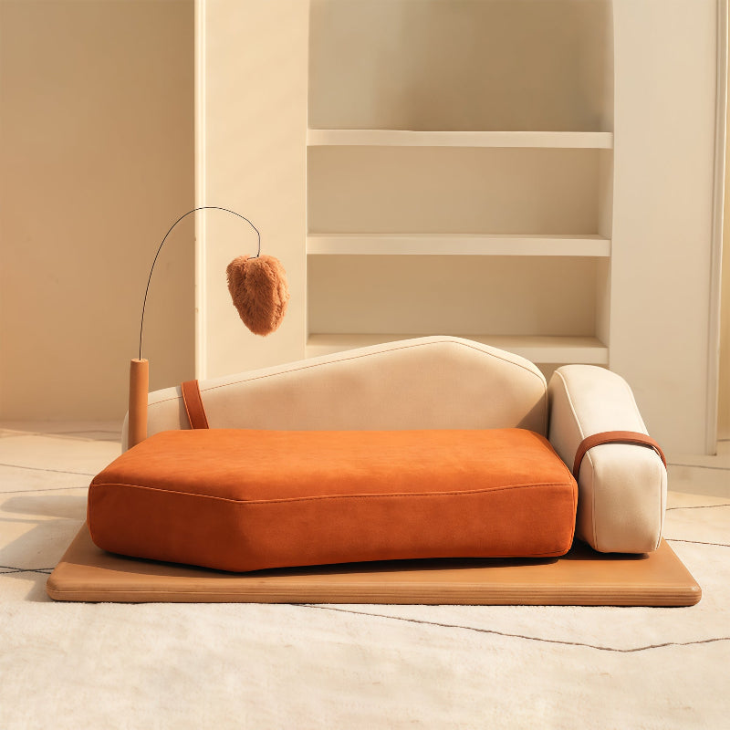 A modern orange and cream cat sofa bed featuring a thick plush cushion, curved backrest, wooden base, and a dangling teaser toy.