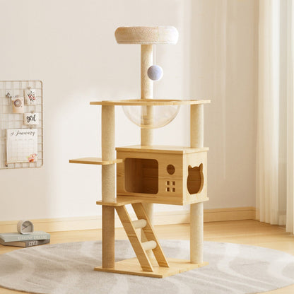 Modern wooden cat tree tower featuring a cat condo enclosure, clear acrylic space capsule hammock, top plush perch, and sisal scratching posts in a cozy room