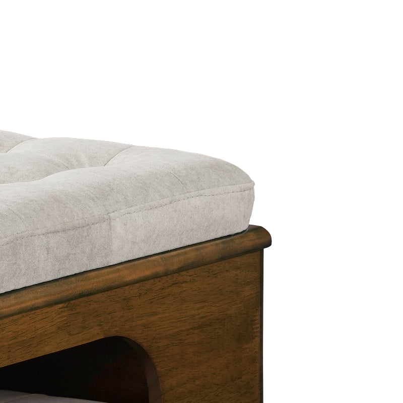 A close-up view of the thick tufted fabric cushion and smooth wooden corner frame of an ottoman cat house on a white background.
