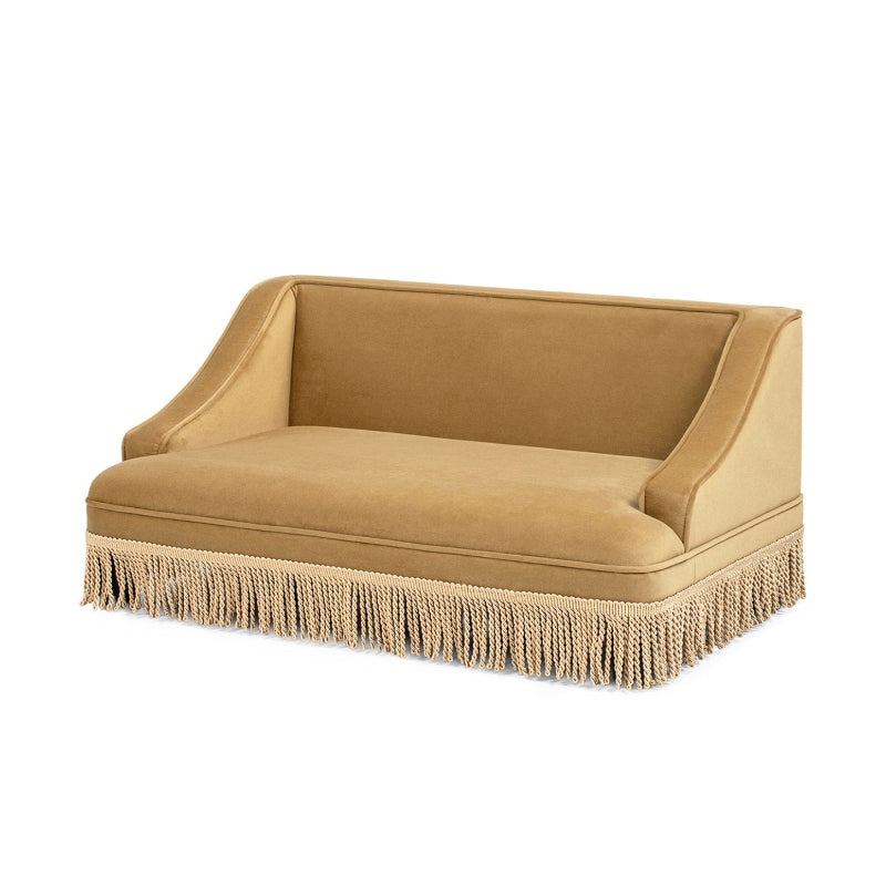 An isolated studio shot of a vintage mustard yellow velvet cat sofa bed featuring a plush cushion, sloping armrests, and decorative beige tassel fringe trim.