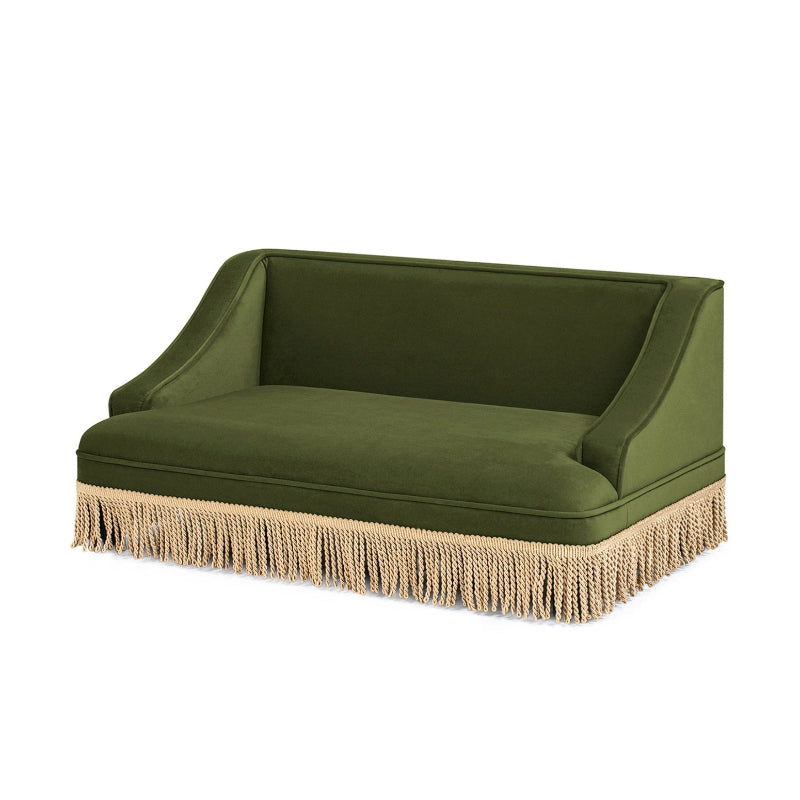 An isolated view of a vintage olive green velvet cat sofa bed featuring a plush cushion, sloping armrests, and cream tassel fringe trim.